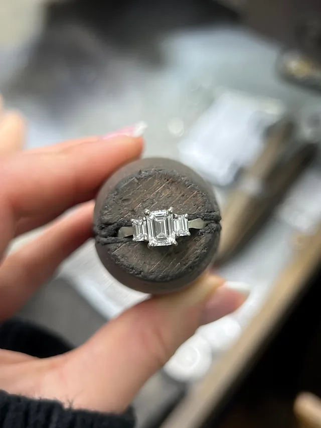 An emerald-cut three-stone ring held in setting wax